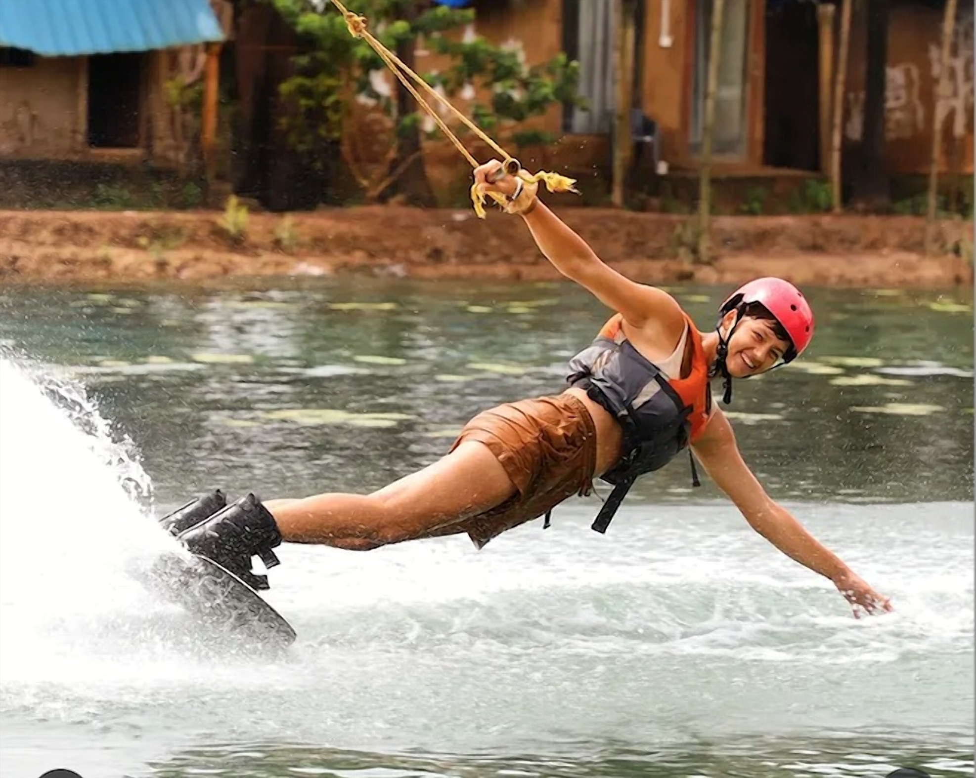 Smiling wakeboarder reaching down to touch the water on Om Lake